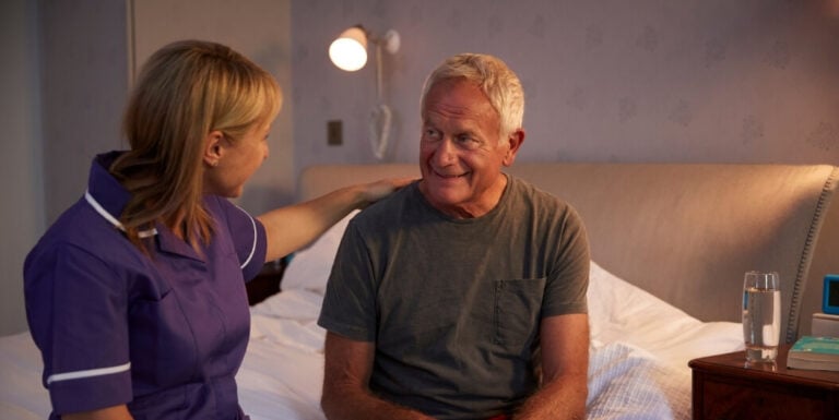Female Nurse Checking on Senior Male Resident at Night at a Memory Care Facility