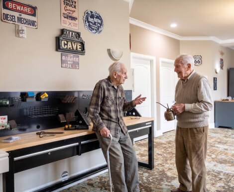 Two Elderly Men Chatting in Garage Lounge at Memory Care Facility Two Elderly Men Chatting in Garage Lounge at Memory Care Facility